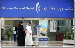 (FILES) In a file picture dated 07 March 2007 an Emirati couple walk past the National Bank of Dubai at a shopping centre in the Gulf Emirate. Shareholders of two banks in the United Arab Emirates have approved a merger deal, creating the biggest bank in the Gulf region, with assets of 165 billion dirhams (45 billion dollars), the offical WAM news agency said 06 September 2007. Shareholders gave the green light to the tie-up of the Emirates Bank International (EBI) and the National Bank of Dubai (NBD) at special general assemblies over the 05 and 06 September. AFP PHOTO/KARIM SAHIB (Photo credit should read KARIM SAHIB/AFP/Getty Images)